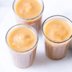 three clear glasses filled with homemade apple juice on a white table