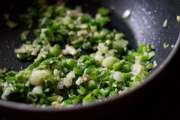ginger, garlic, spring onions, green capsicum and green chilies in a pan