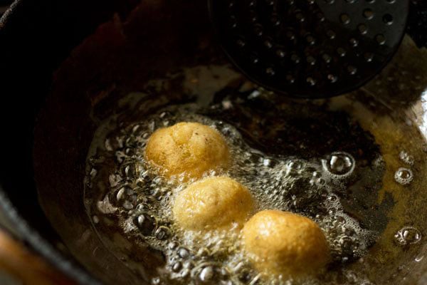lightly fried falafel being turned over in hot oil.