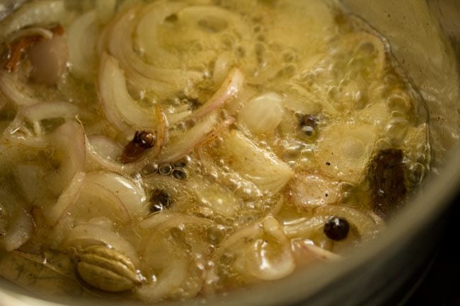 sliced onions added to ghee in the pan