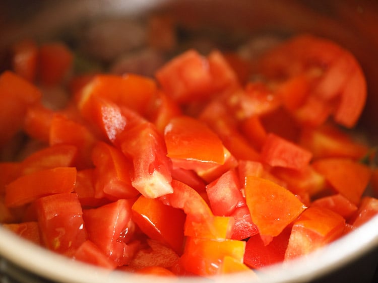 adding tomatoes to the pan
