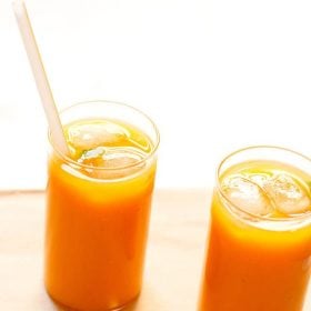 mango tea in two glasses with ice cubes and a straw in one glass
