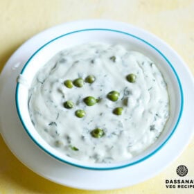 methi matar malai in a white bowl with a light blue rim, garnished with a few peas.