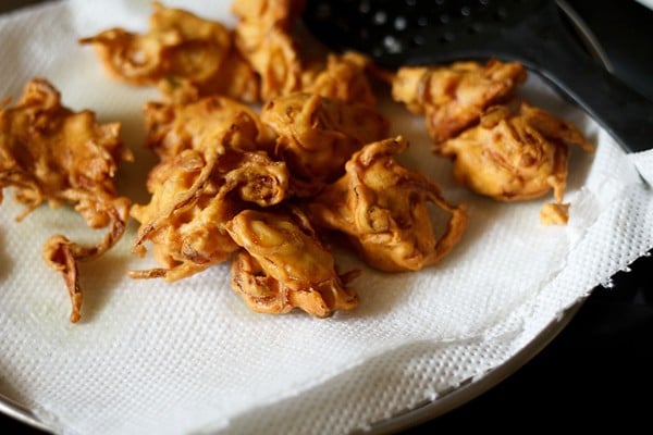 fried onion pakoda placed on kitchen paper towel. 
