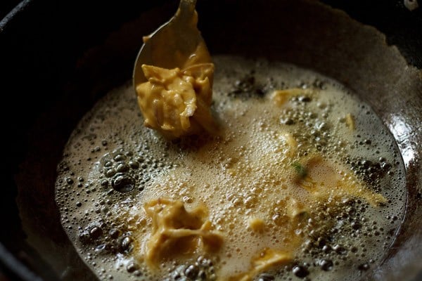 adding spoonful of prepared onion pakora batter in hot oil. 