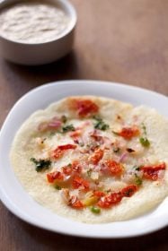 tomato uttapam served on a white plate.