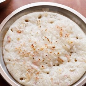 onion uttapam served on a steel plate.