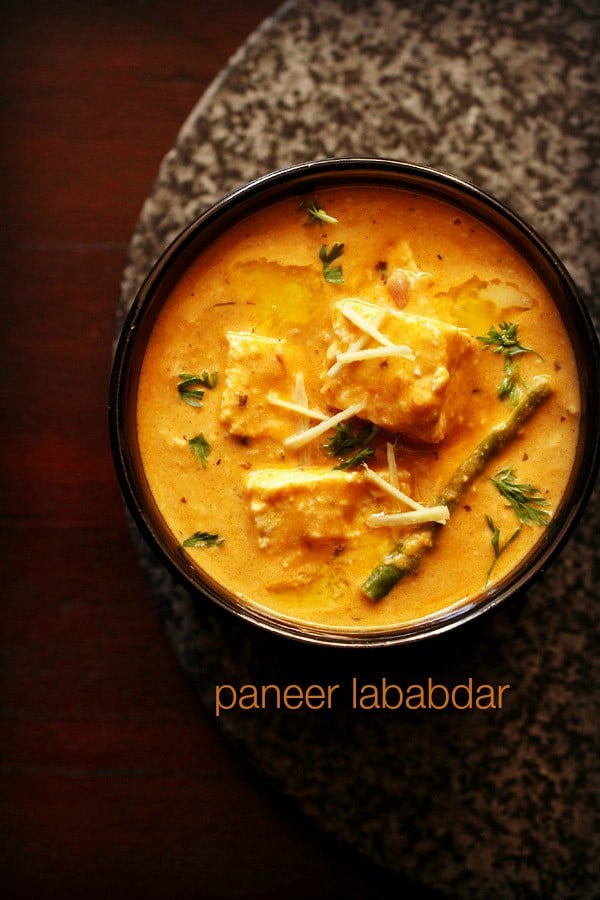 paneer lababdar served in a black bowl with ginger julienne on top and text layover.