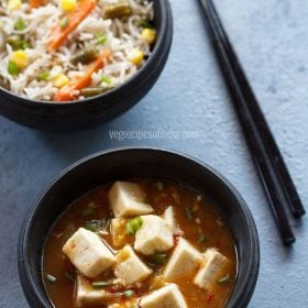 schezwan paneer served in a back bowl with a side of fried rice and text layover.