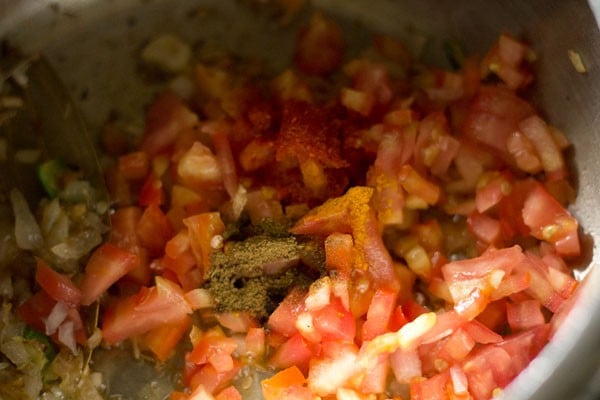 ground spices on chopped tomatoes in cooker.